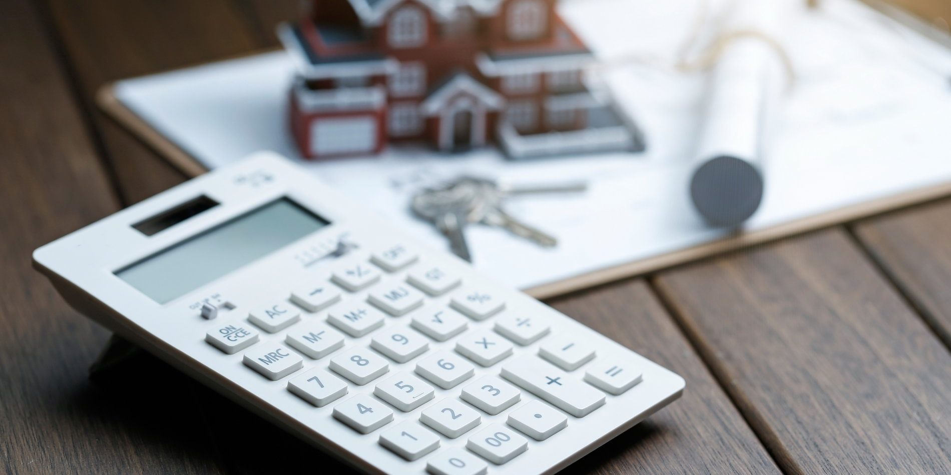 a calculator in front of a Villa house model with a blueprint